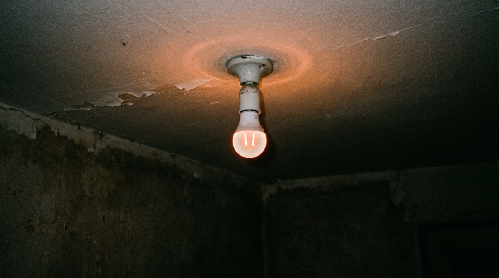 LED bulb glowing faintly in a dark room with the smart switch turned off, showing the ghost glow caused by no-neutral trickle current