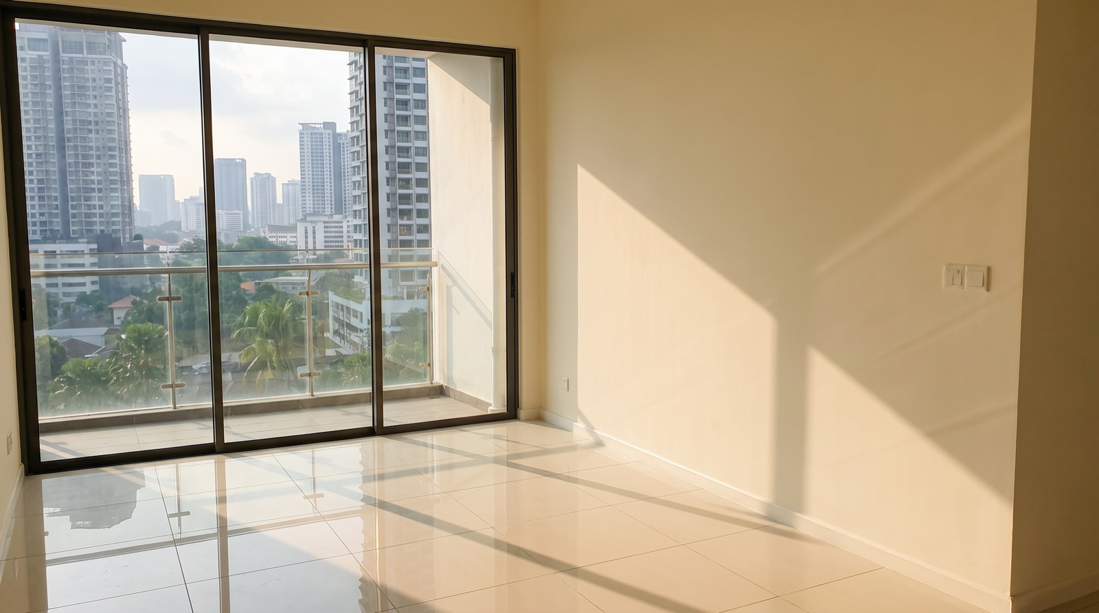 An unfurnished corner of a new condominium show unit under development, bare painted walls, a capped-off network point and an unlit socket plate on the wall, shot to show what a buyer is actually handed over